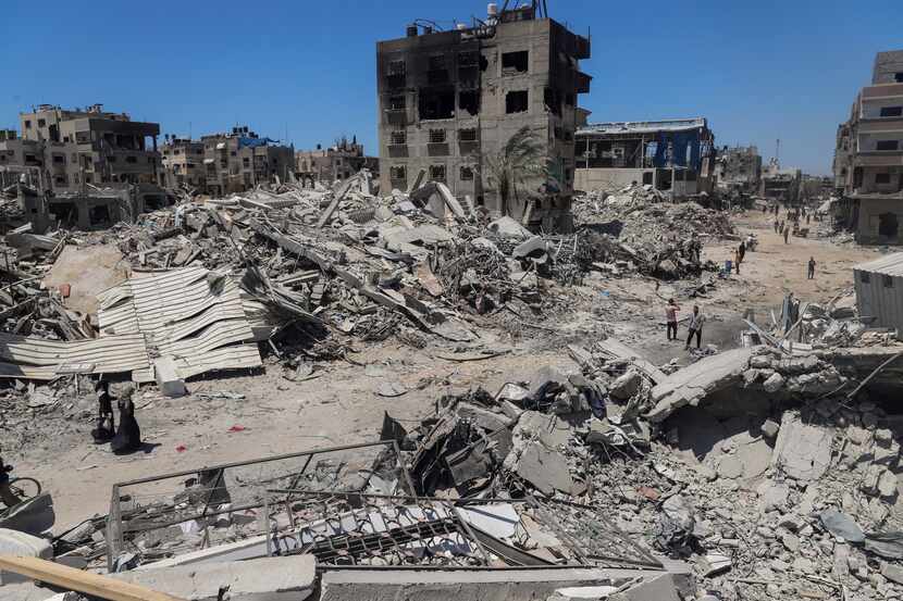 Palestinians walk through the destruction in the wake of an Israeli air and ground offensive...
