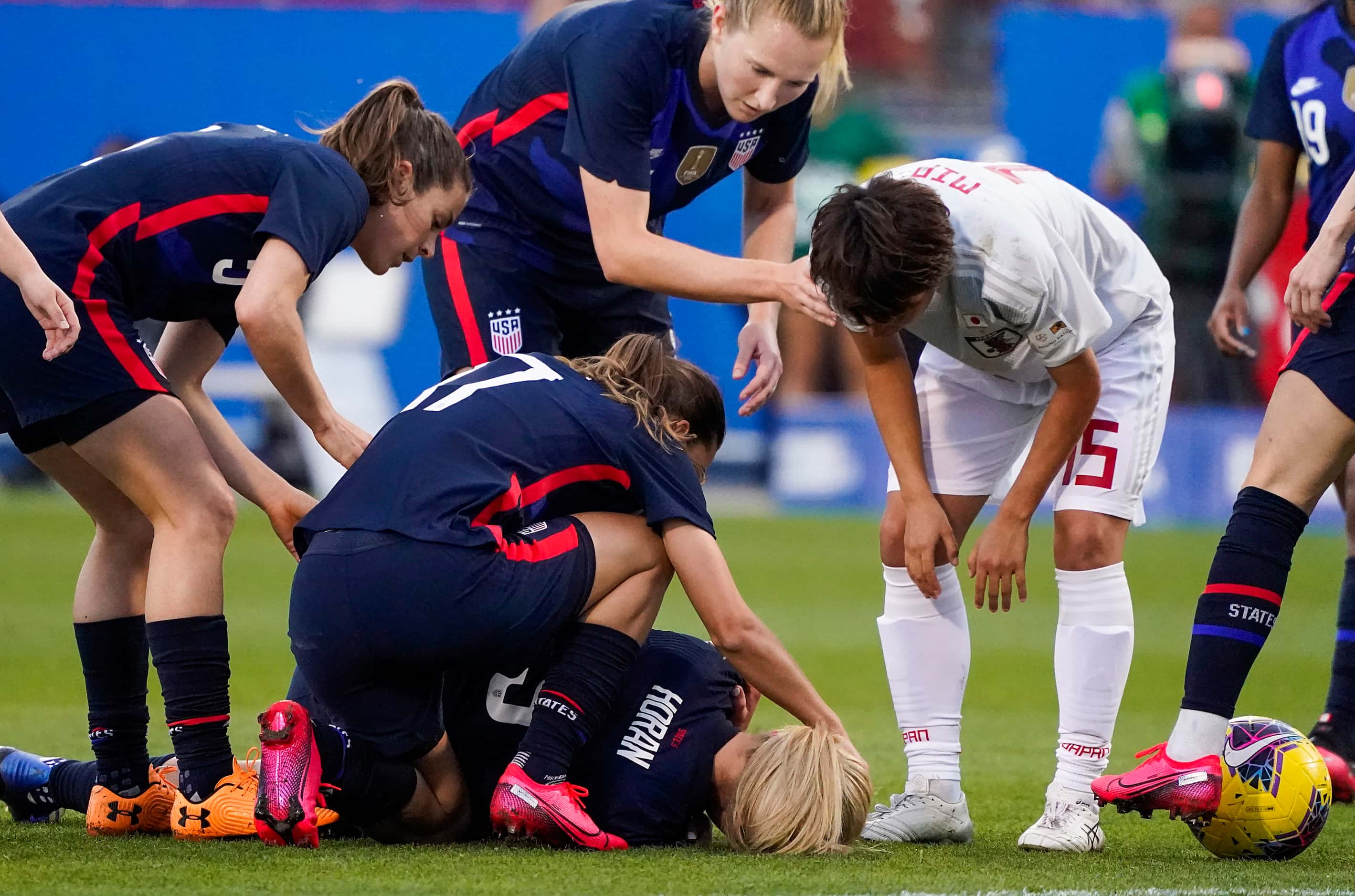 USA midfielder Lindsey Horan is tended to after being taken out by Japan forward Mina Tanaka...