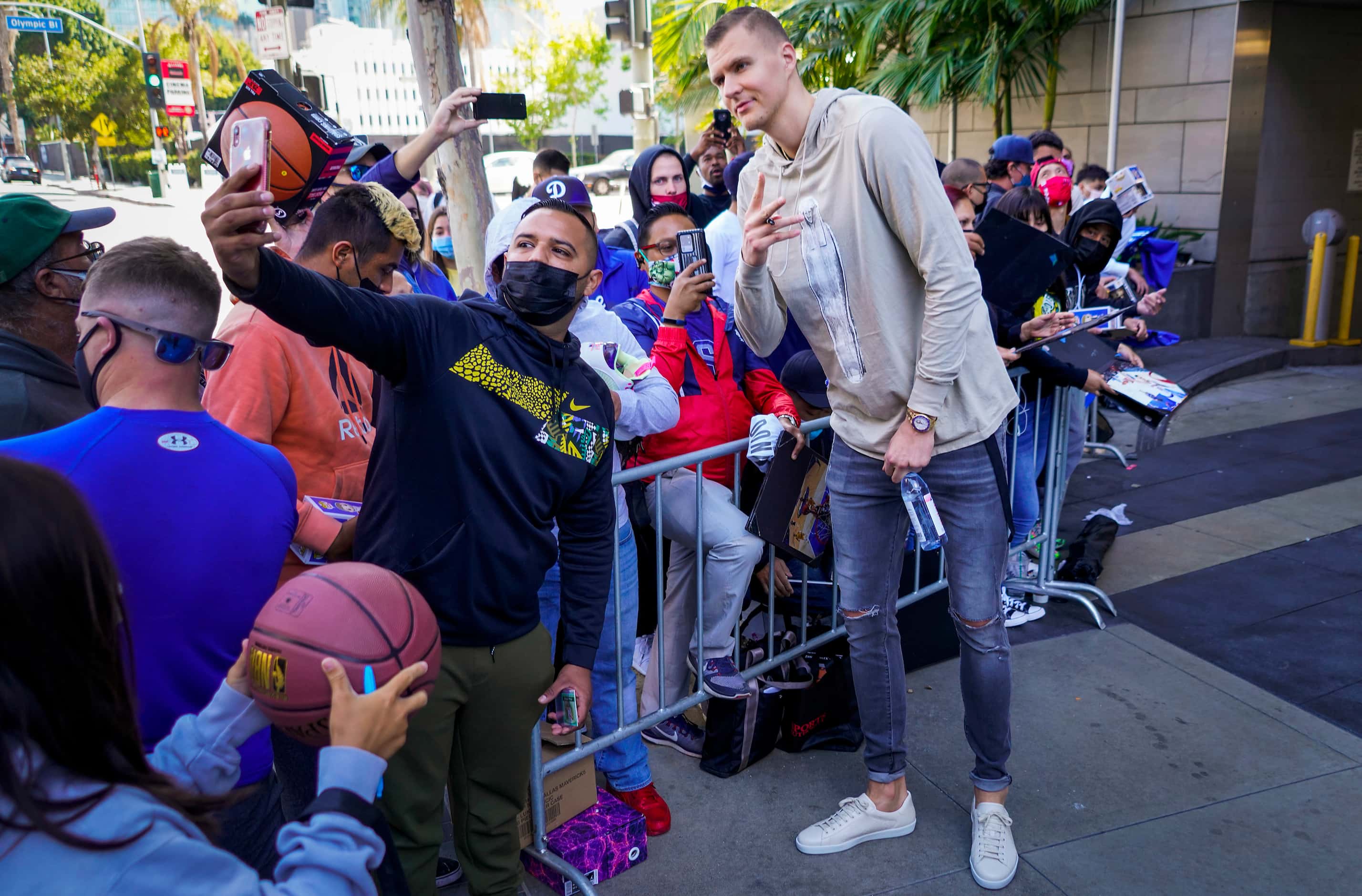 Dallas Mavericks center Kristaps Porzingis poses for a selfie with fans as the team leaves...