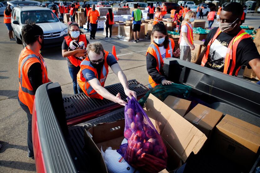A team of volunteers loaded vehicles with bagged fruits and vegetables, cartons of dry goods...
