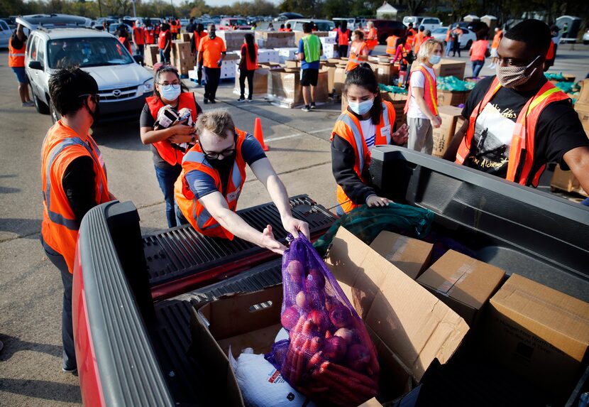 A team of volunteers loaded vehicles with bagged fruits and vegetables, cartons of dry goods...