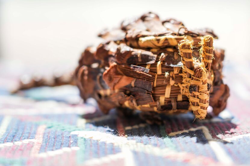 A basket in the shape of an armadillo, made from the needles and cones of a longleaf pine,...