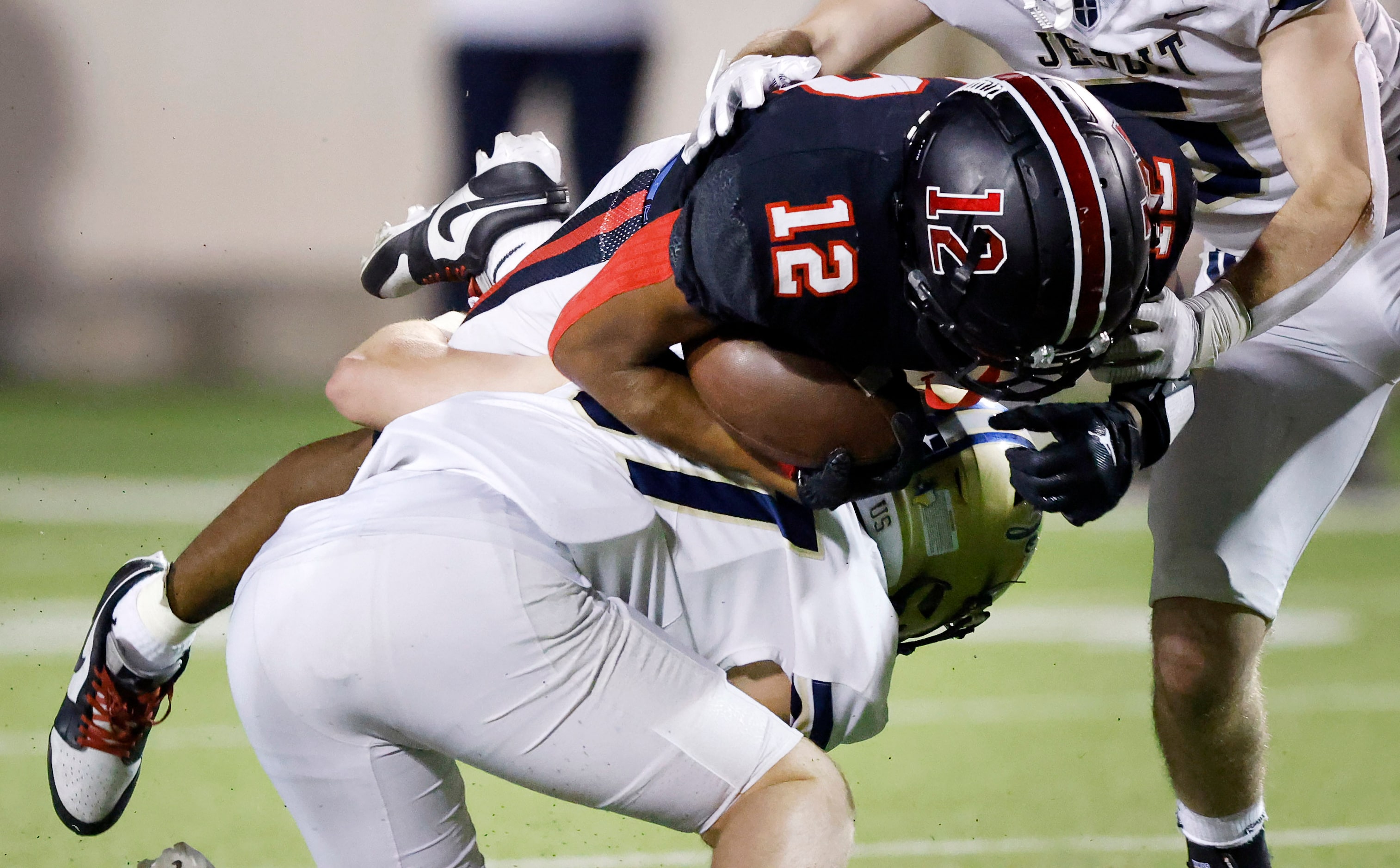 Lake Highlands receiver Franklon Evans (12) dives over a Jesuit Dallas defender as he’s...