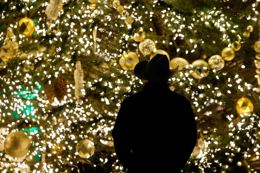 Spectators are silhouetted against the lit Christmas tree in downtown McKinney on Thursday,...