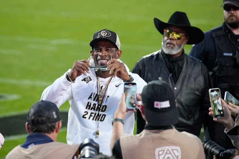 Colorado head coach Deion Sanders, center, puts on his sunglasses after acknowledging the...