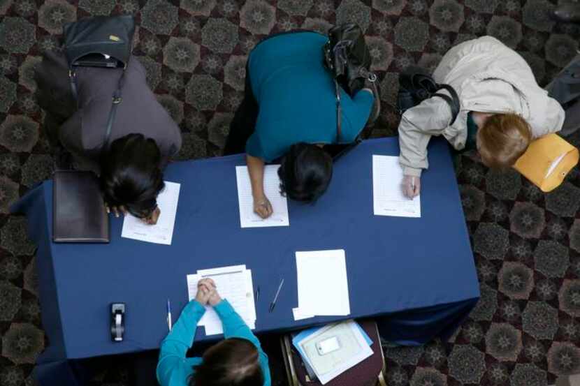 FILE - In this Jan. 22, 2014, file photo, job seekers sign in before meeting prospective...