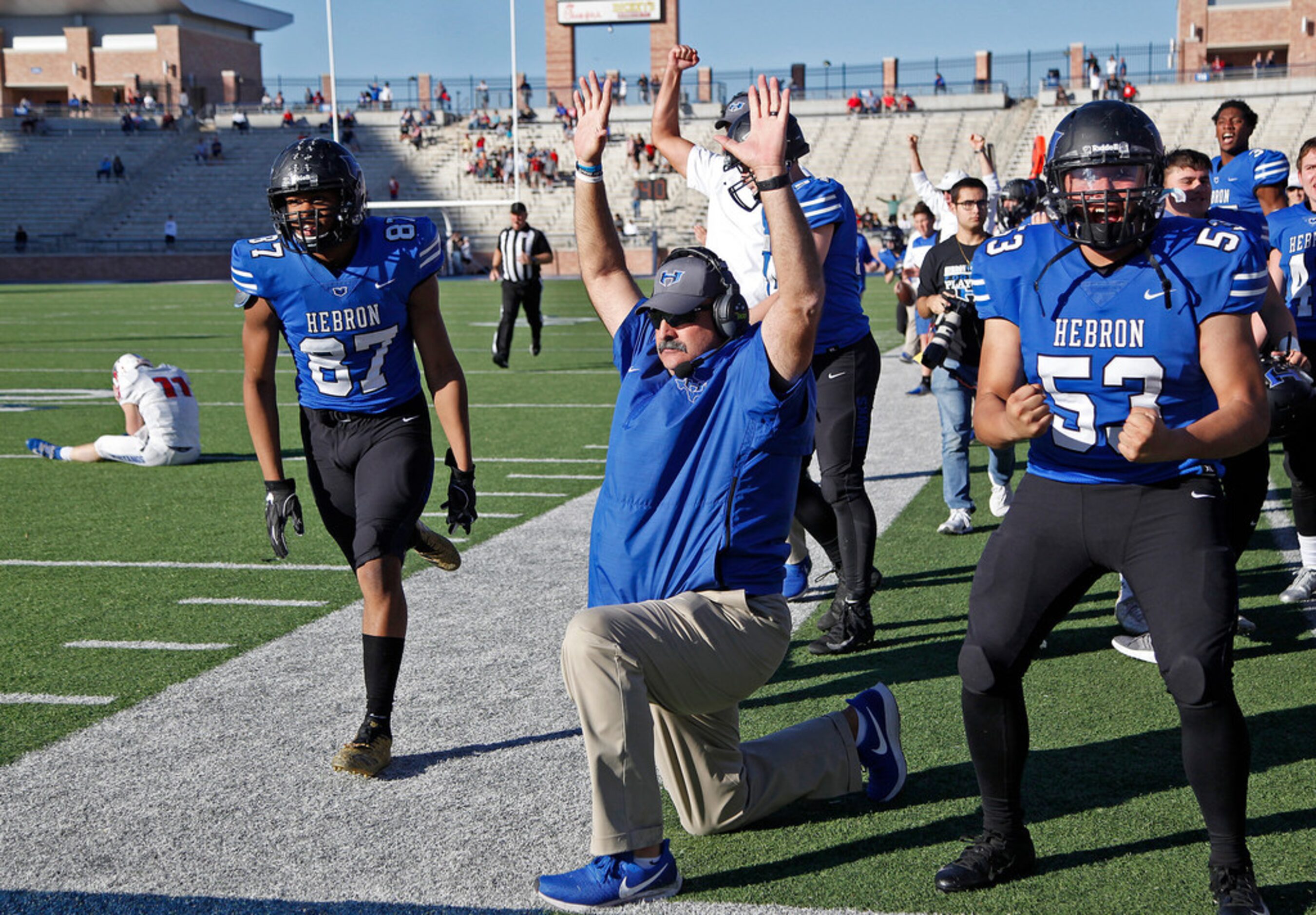 Players on the Hebron sideline erupt around head coach Brian Brazil as they watch an...