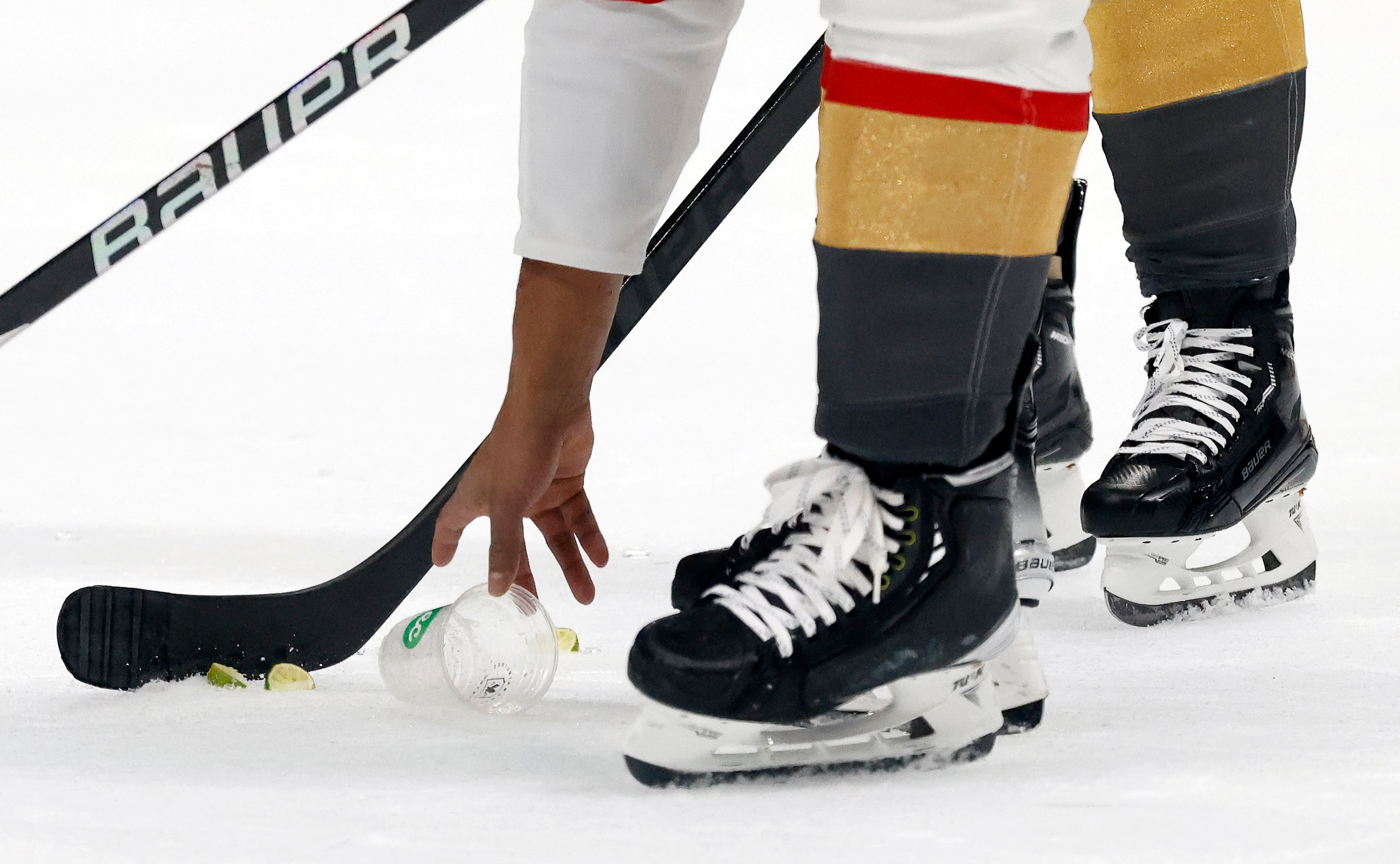 A Vegas Golden Knights player picks up a cup and limes thrown on the ice near the end of the...