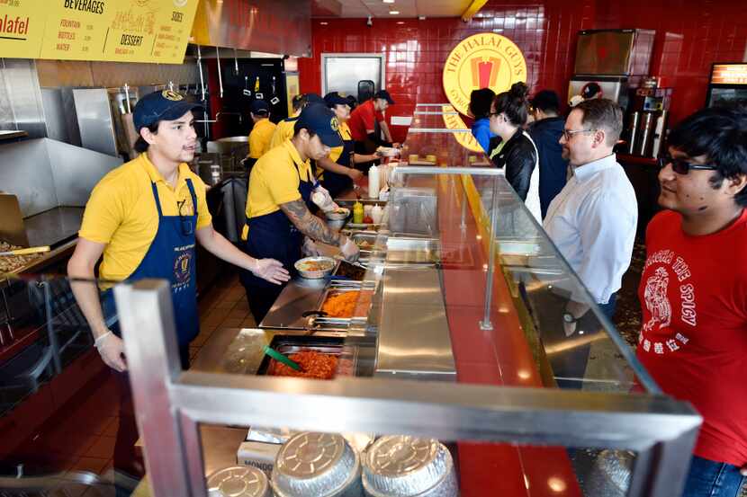 Food server Elijah Layton, left, takes an order from Amann Islam at the a The Halal Guys...