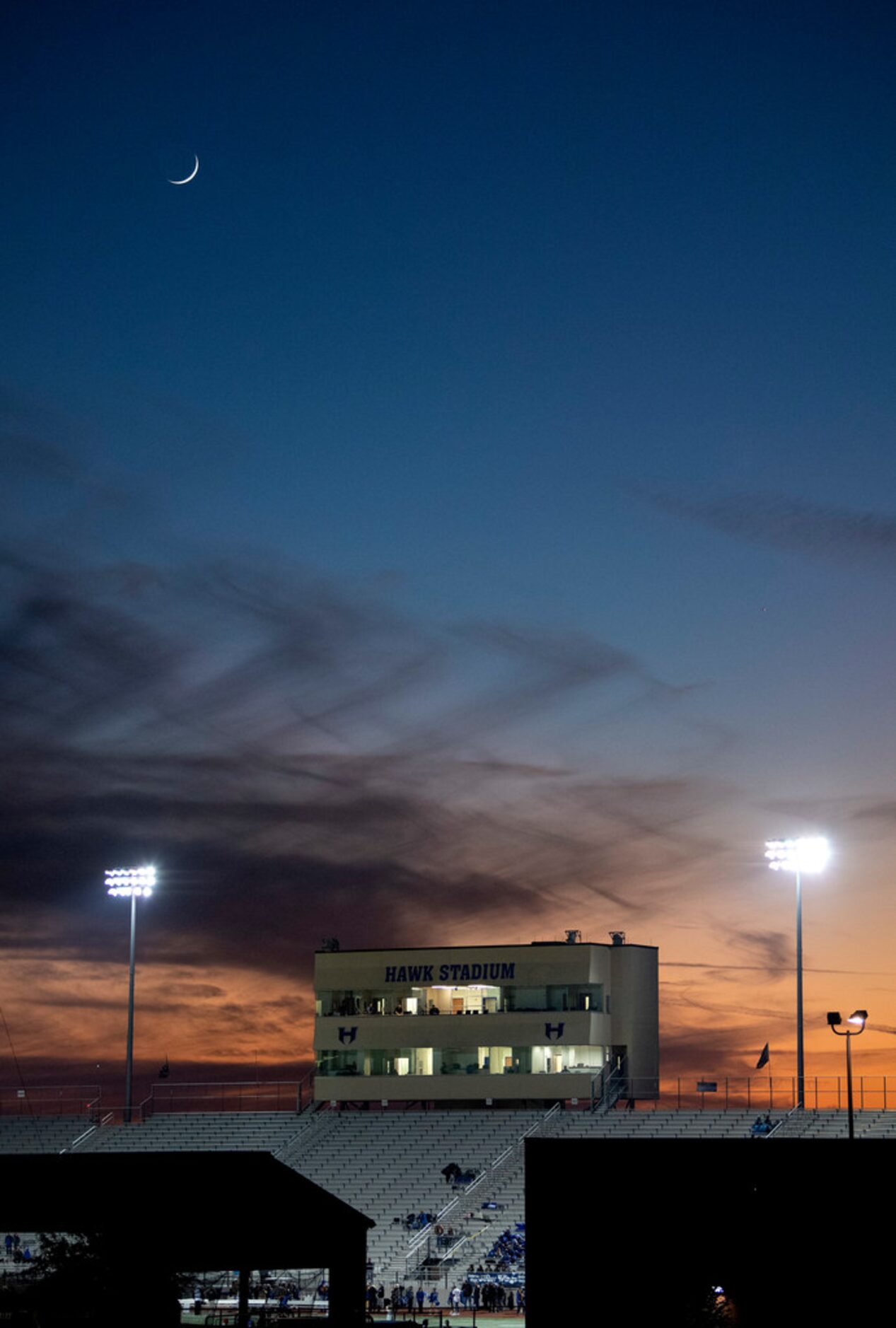 The moon sets over Hawk Stadium before a high school football game between Irving and Hebron...