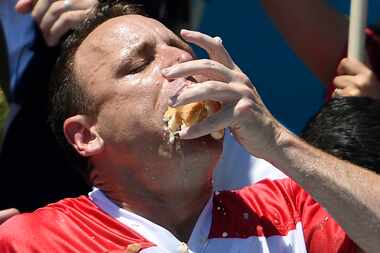 FILE - Joey Chestnut stuffs his mouth with hot dogs during the men's competition of Nathan's...