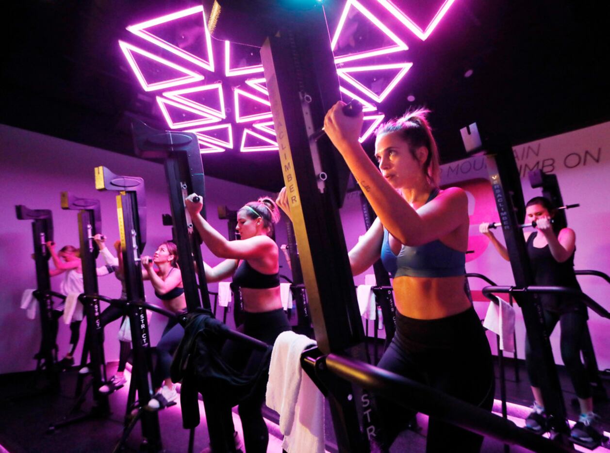 Jennifer Cantelmo (right) works out on the VersaClimber, as lights and music create an...