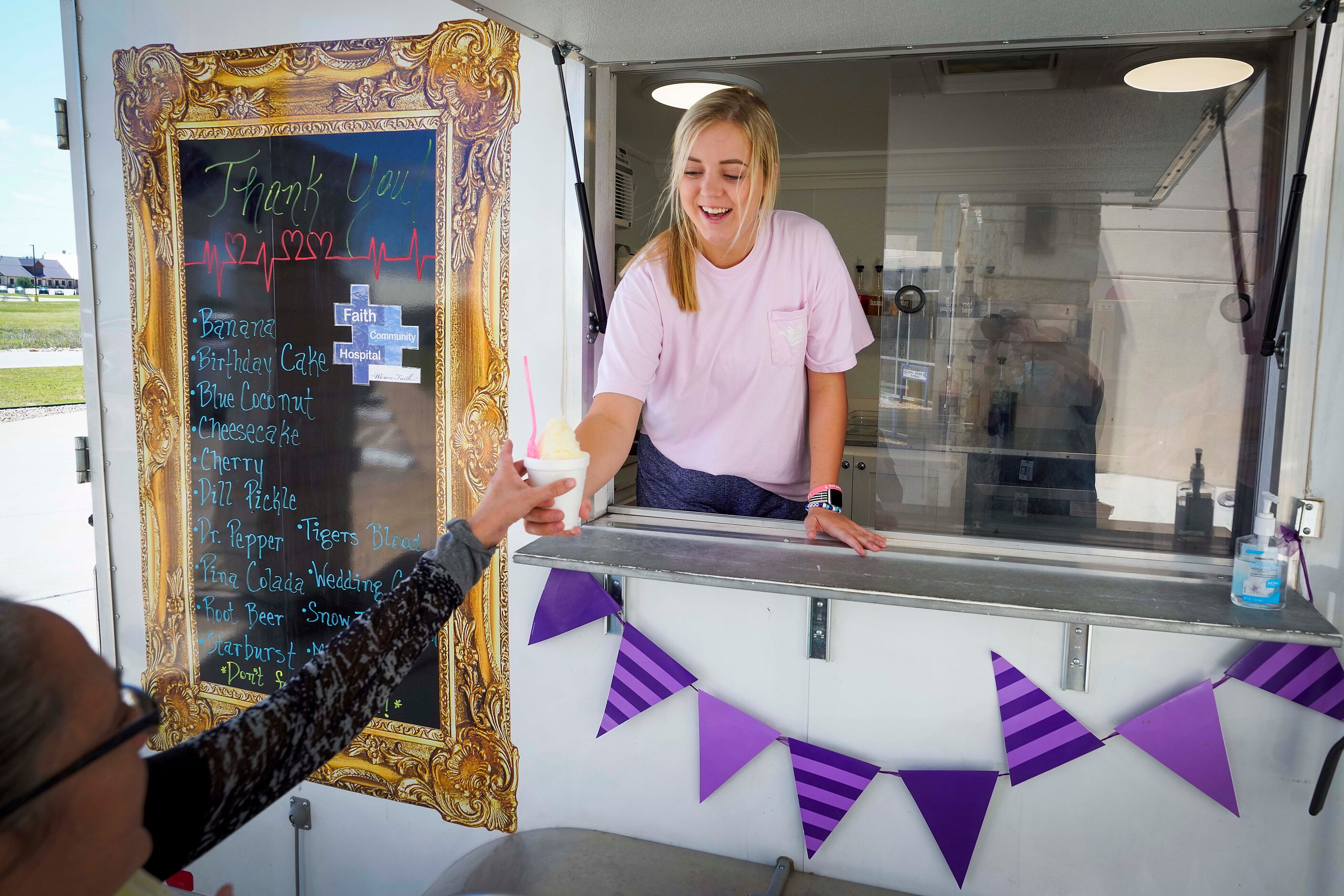 Carli Smith of Sweet Crown Shaved Ice hands a frozen treat to a staff member at Faith...