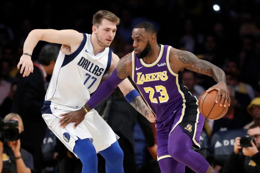 Los Angeles Lakers' LeBron James (23) is defended by Dallas Mavericks' Luka Doncic (77)...