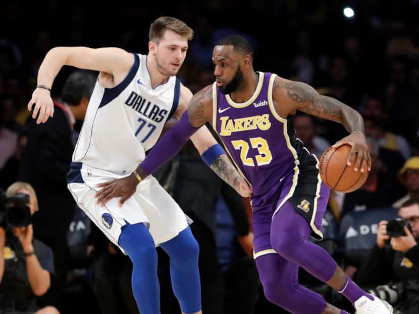 Los Angeles Lakers' LeBron James (23) is defended by Dallas Mavericks' Luka Doncic (77)...