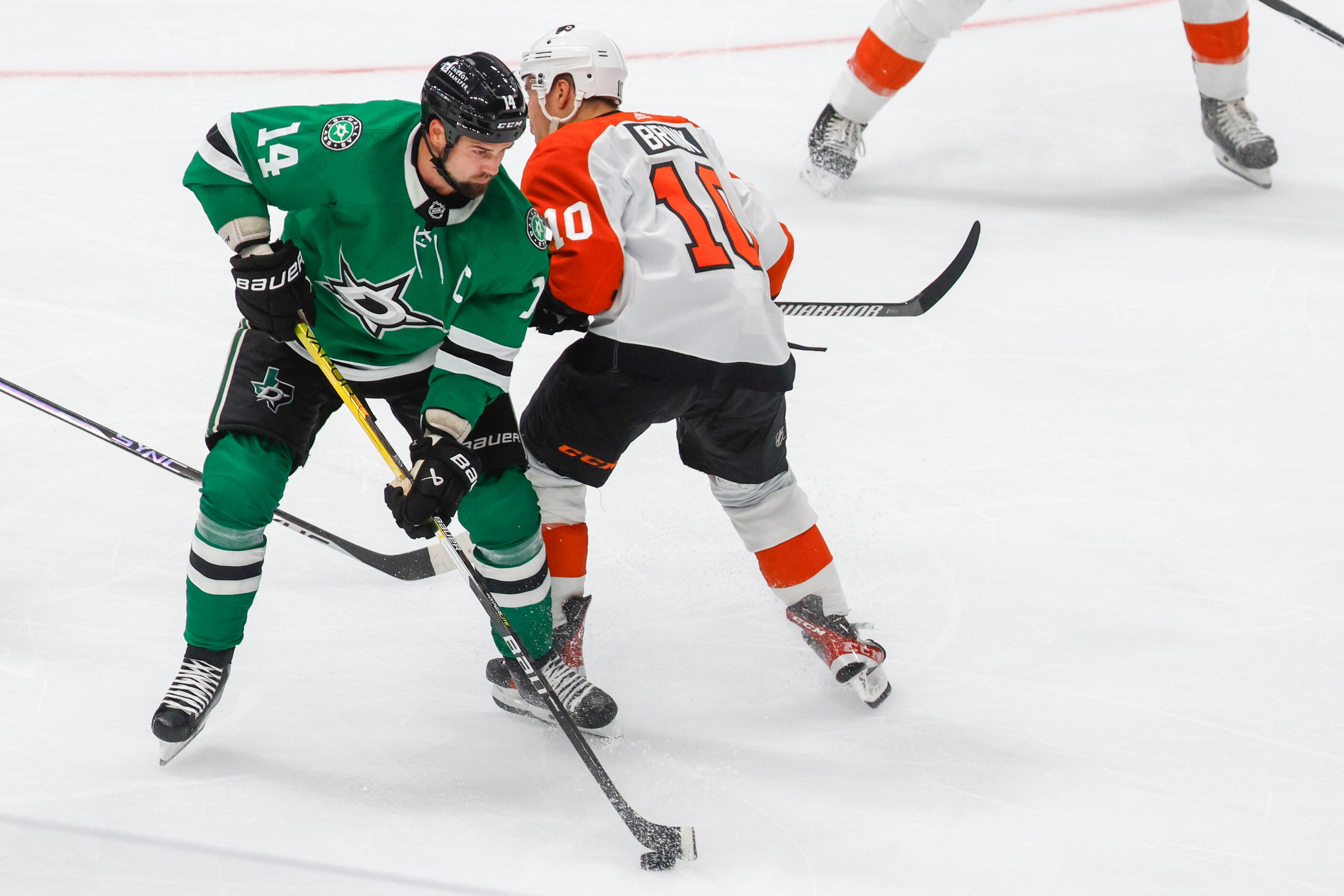 Dallas Stars left wing Jamie Benn (front) handles the puck against Philadelphia Flyers right...