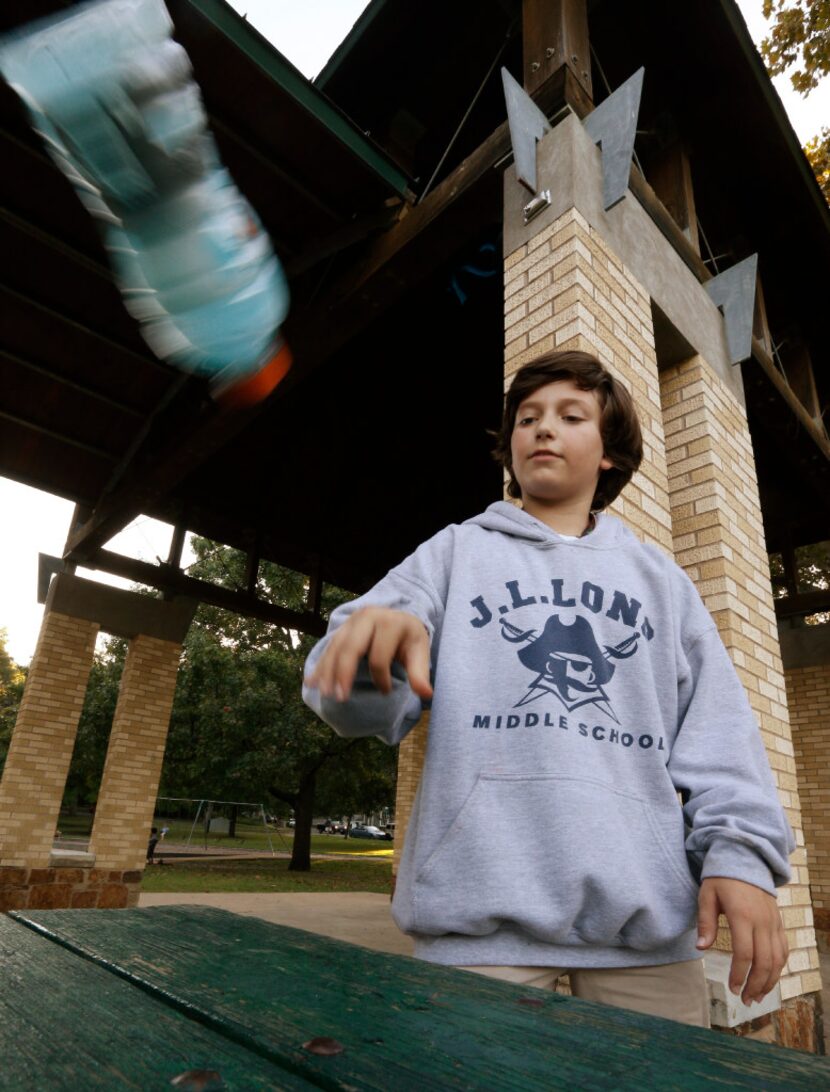 Ian Interrante, 12, demonstrates the flipping bottles game at Lindsley Park in Dallas.