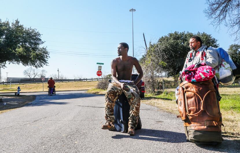 Chris Johnson (left) and Carlton Nalley, who are both homeless, carry their belongings after...