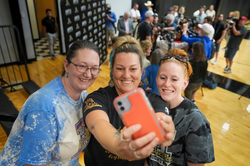 Lela Foster (from left), Jill Hill and Sallee Hedrick take a selfie as Troy Aikman addresses...