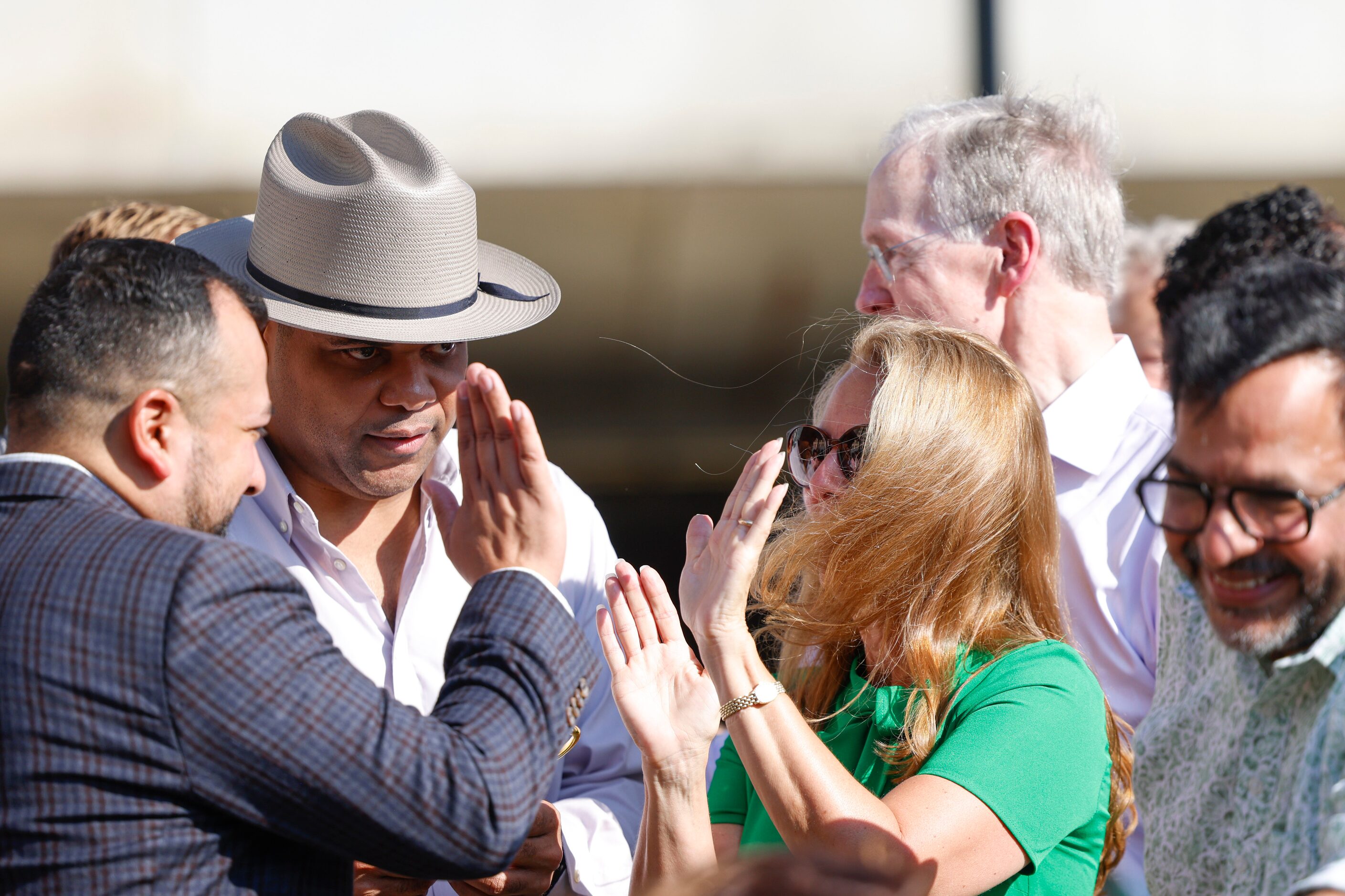 City council member Jesse Moreno (left), past Mayor Eric Johnson (center) high fives...