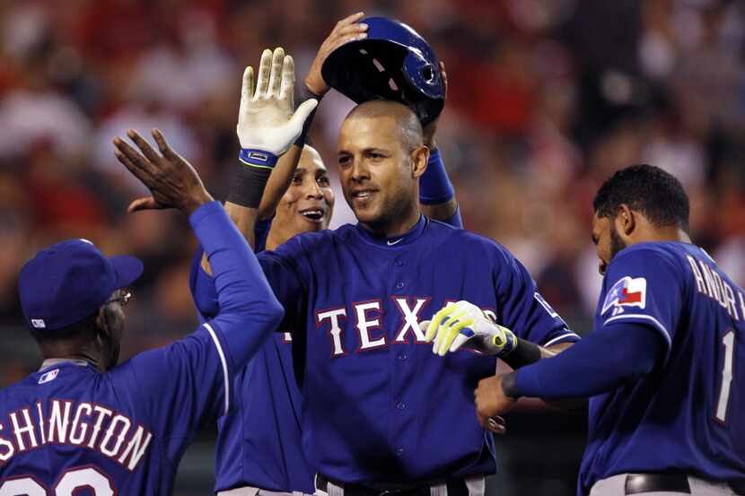 Texas Rangers Alex Rios, center, gets high five from manager Ron Washington, left, and Elvis...
