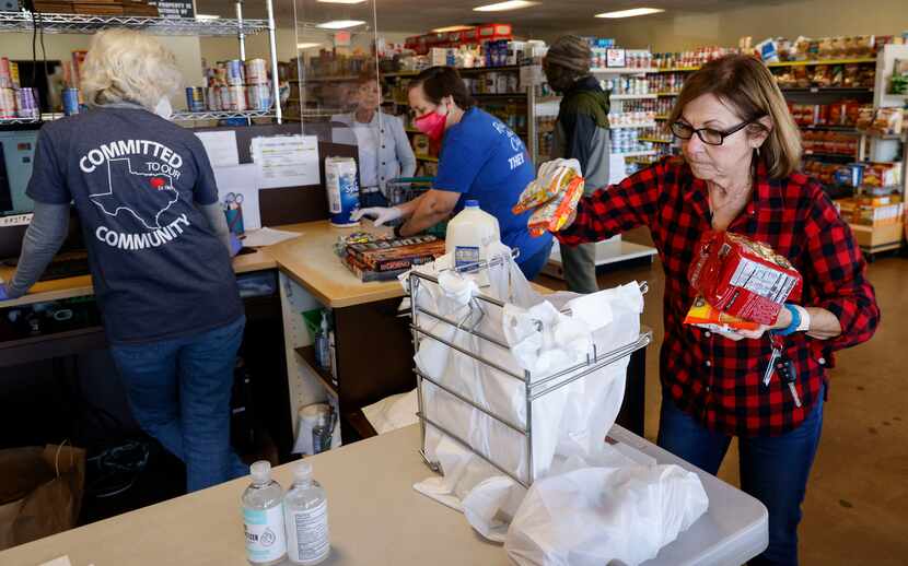 Volunteer Janis Ramirez bags goods at the counter shopped by Pete Sanders at Frisco Family...