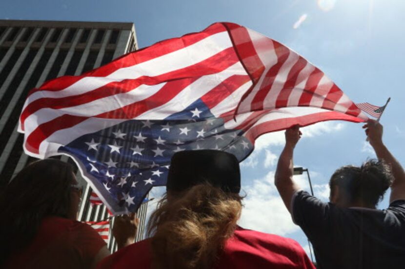 Yazmin Cruz (izq.) y jorge Gallegos llevan la bandera estadounidense durante la Megamarcha...