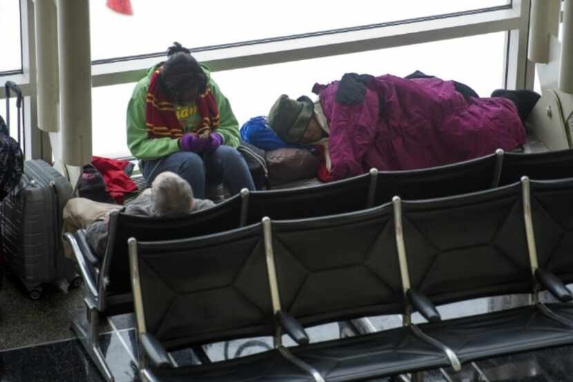 Passengers whose flights were canceled Thursday pass the time at Washington's Ronald Reagan...