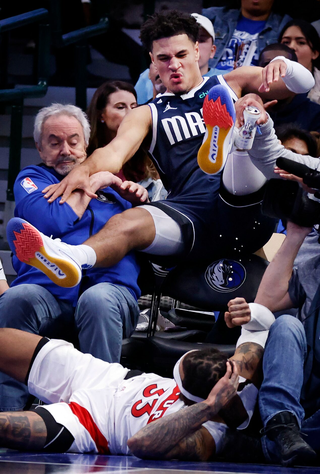 Dallas Mavericks guard Josh Green (8) goes flying into the lap of fans as he and Toronto...