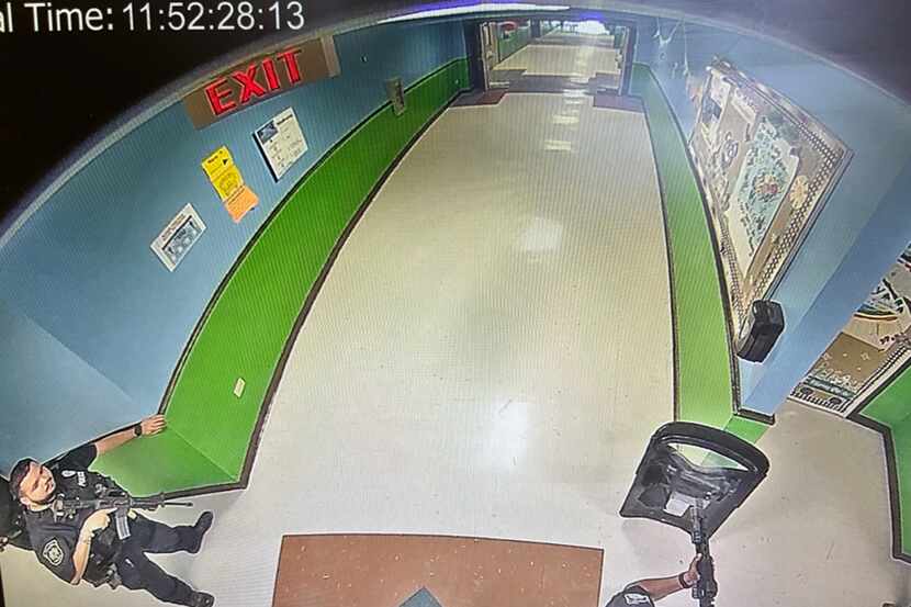 Multiple police officers stood in a hallway at Robb Elementary School armed with rifles and...