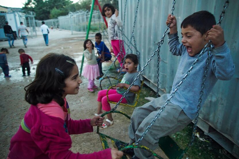 Children play on swings at a refugee camp on the northeastern Greek island of Chios,...