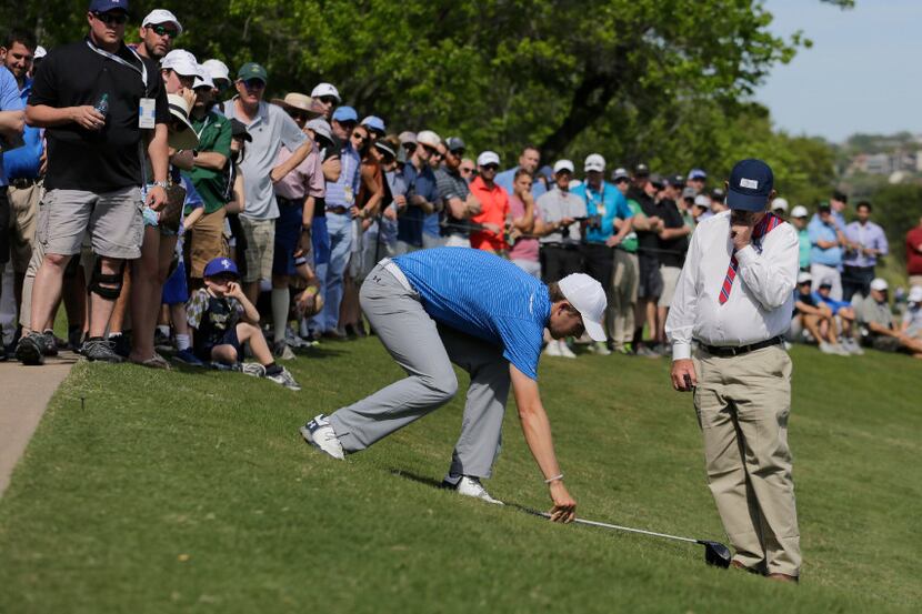 With the help of an official, Jordan Spieth, front left, prepares to take a drop after his...