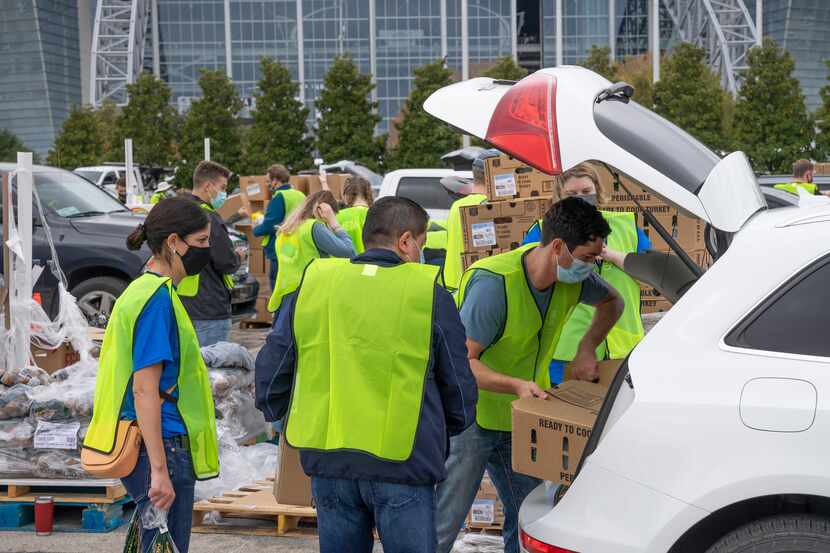 Volunteers load food into a vehicle at the TAFB's Thanksgiving-themed food distribution...