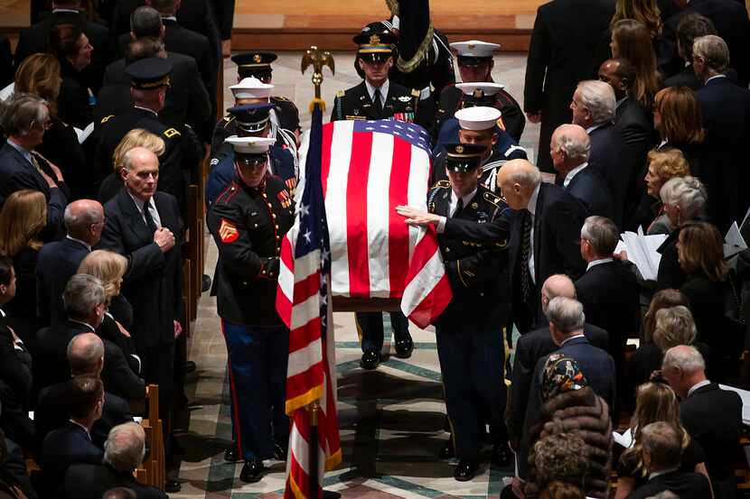 Former Sen. Alan Simpson reaches out to touch the flag-draped casket as a military honor...