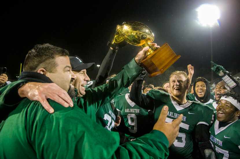 Head coach Scott Peach raises a trophy after winning the high school football game between...