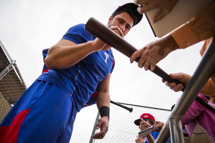 Texas Rangers outfielder Joey Gallo autographs a bat for a fan after practicing at the...