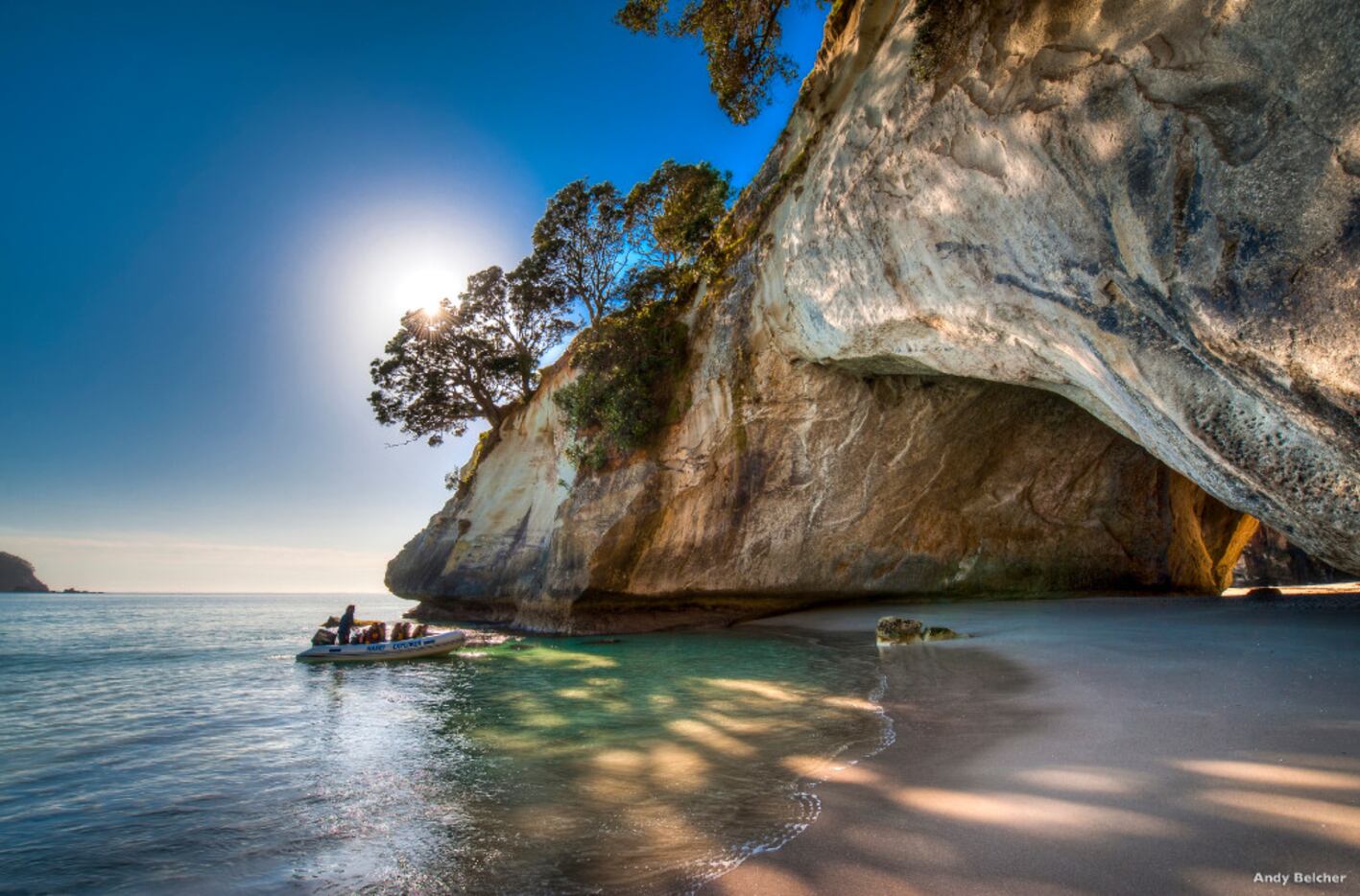 A boat heads toward the natural stone arch at Cathedral Cove on the North Island's...