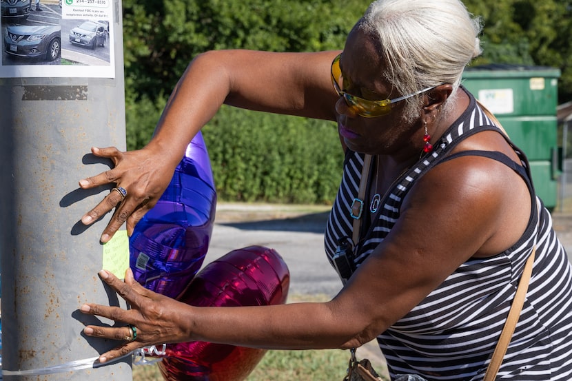 Oak Cliff resident Jillian Mitchell leaves a note on a light pole in honor of Dallas police...