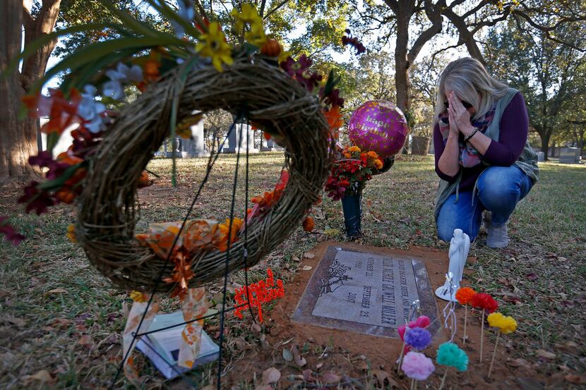 Angela Norris prays while she visits the grave of her daughter, Taylor Gruwell, at Greenwood...