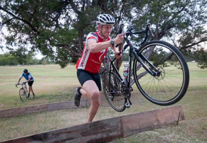 
Chauncey Deller carries his bike over an obstacle during a training ride at Flag Pole Hill.
