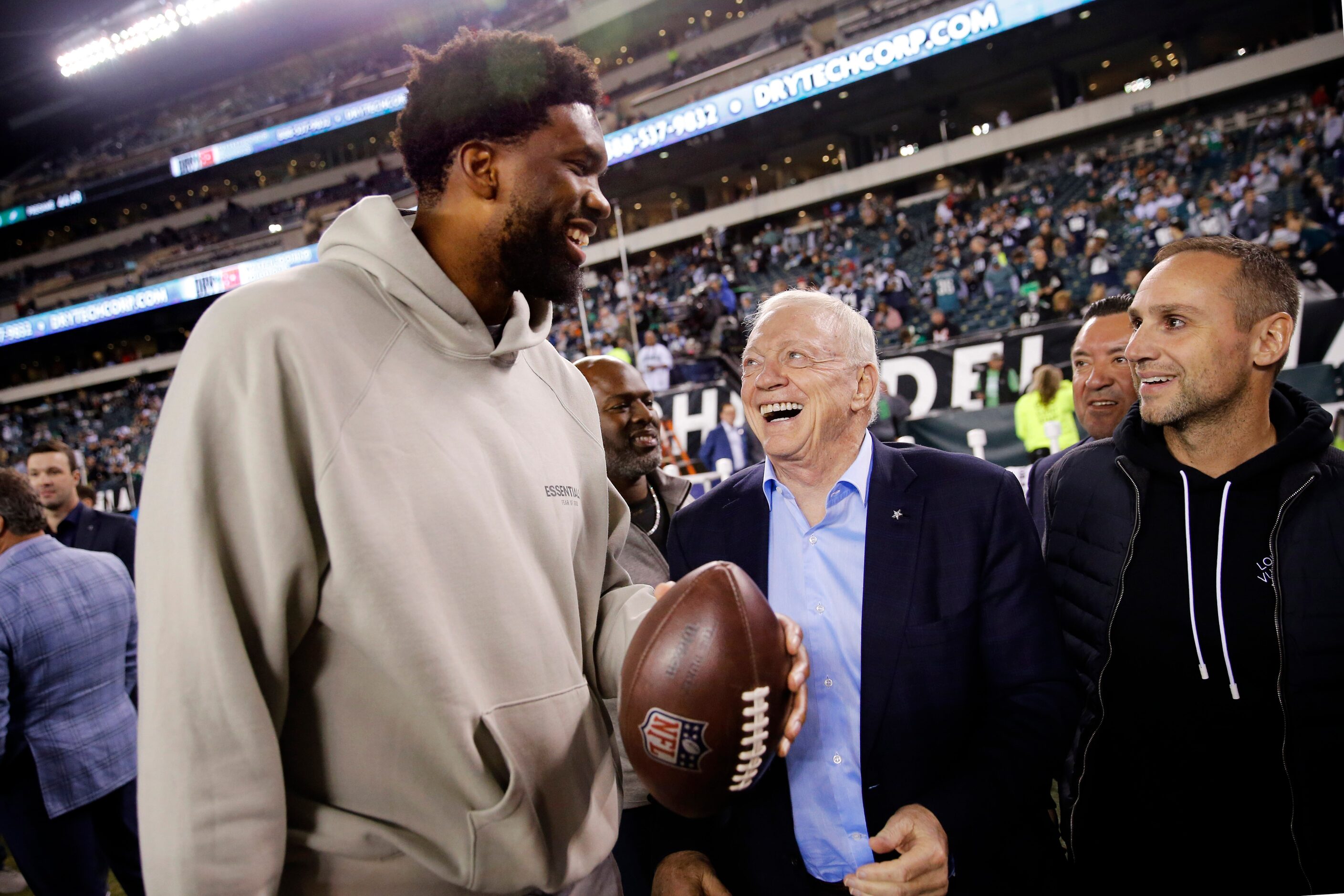 Philadelphia 76ers basketball player Joel Embiid laughs with Dallas Cowboys owner Jerry...