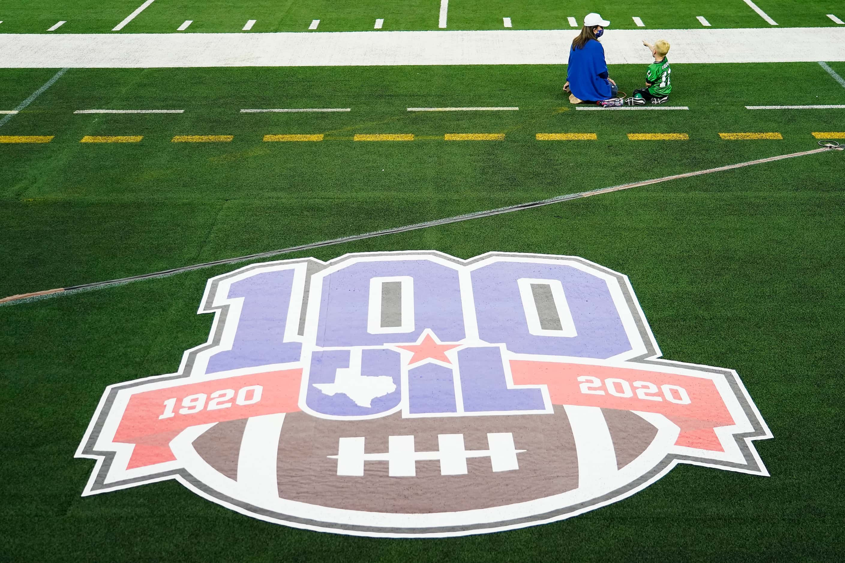 Elizabeth Dodge sits on the field with her grandson Tate, 5, as the teams warm up before her...