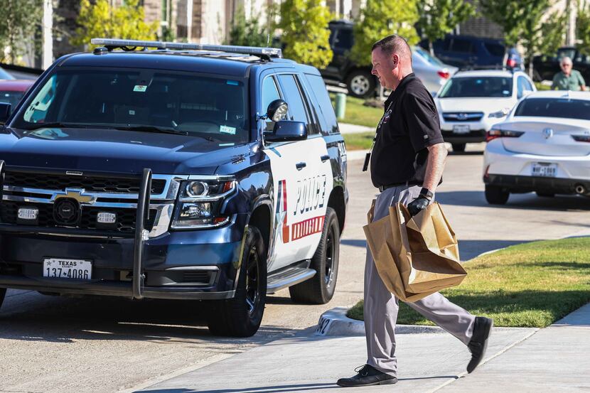 An Arlington police officer carries bags of evidence from Timothy George Simpkins' home.