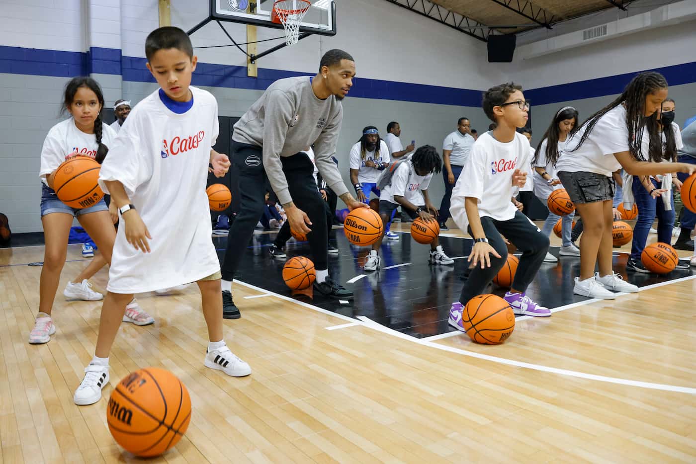 Dallas Mavericks power forward P.J. Washington does basketball drills with children in a...