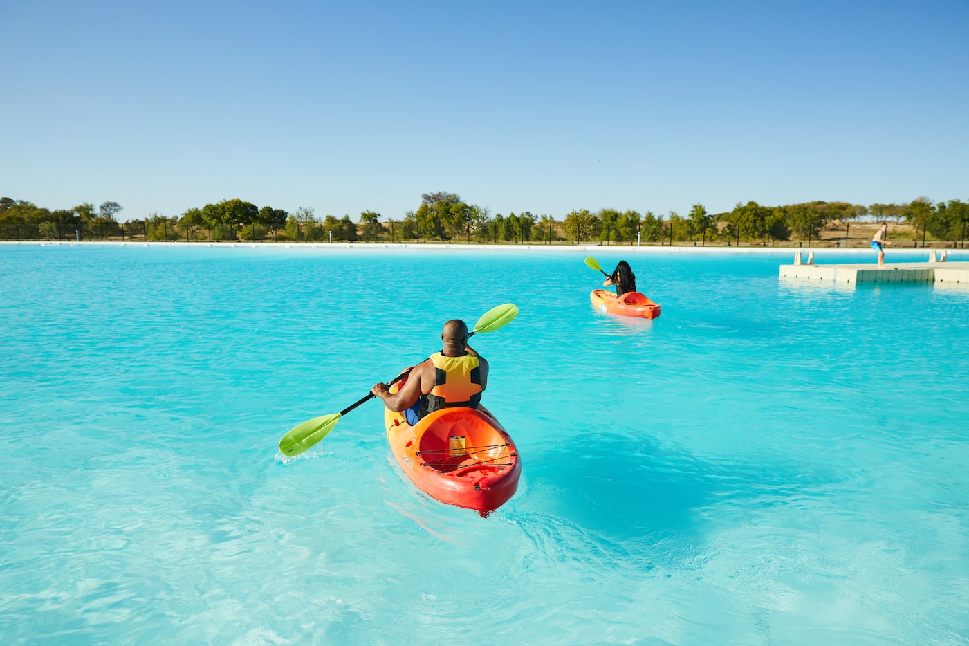 Two people in kayaks on a blue lagoon