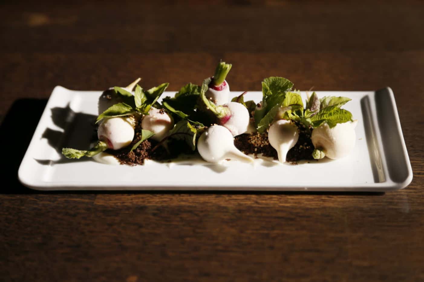 Chef Kyle McClelland's radishes cloaked in butter and radish greens on rye-crumb "soil"...