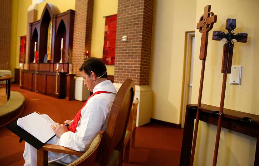 Father Clayton Elder looks over the online schedule for their Holy Thursday service and...