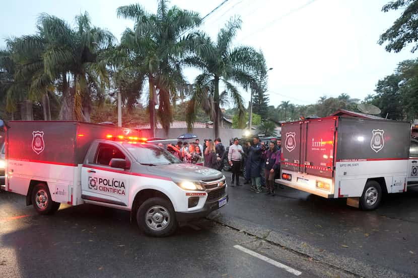 Police vehicles used to carry bodies arrive at the gated community where a plane crashed in...