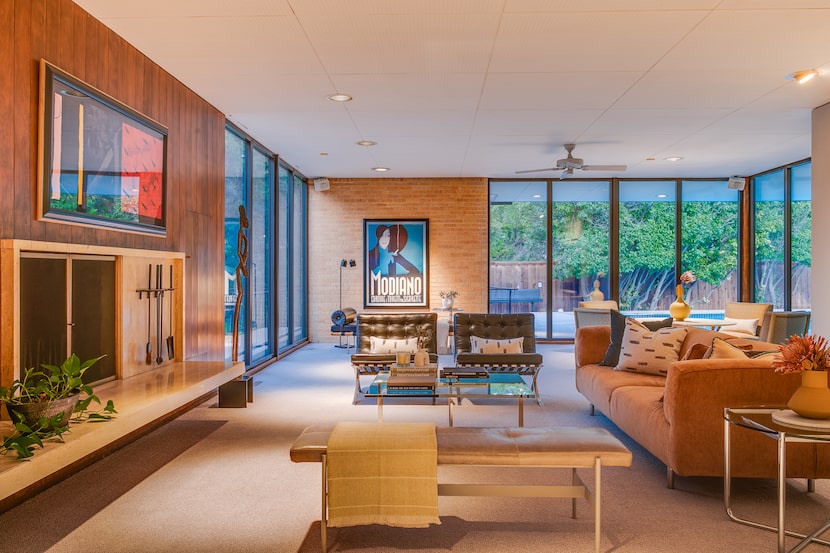 Midcentury modern living room with large windows, seating arrangement in front of fireplace