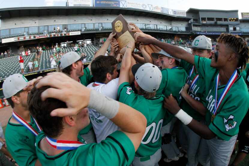 Southlake Carroll players scramble to touch the state championship trophy after it was...